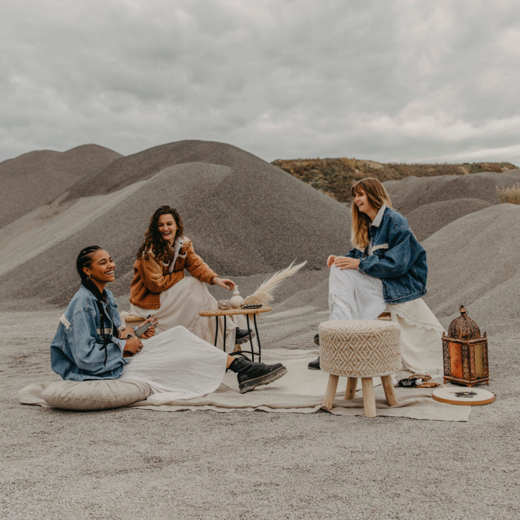 three boho girls sitting laughing making music